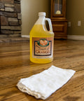 Bottle of Touch of Oranges cleaner and cloth on hardwood floor
