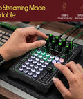Close-up of hands operating a Live Broadcast Sound Card And Rechargeable Mixer Kit with Condenser Microphone on a desk.