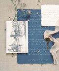 Vintage stationery set with blue and white textured paper, illustration, and a decorative key on fabric background.