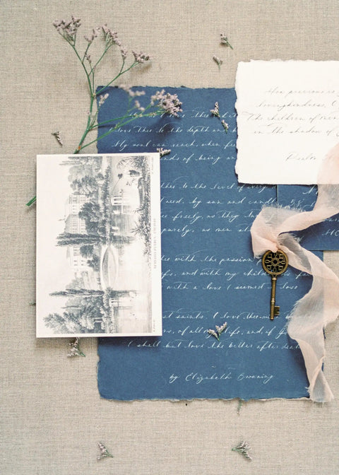 Vintage stationery set with blue and white textured paper, illustration, and a decorative key on fabric background.