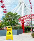 Four Pack 24 Inch Slow Down Kids At Play Sign Reflective Double Sided Street Safety Signs With Portable Handles For Neighborhoods Yards Schools And Parks Yellow in front of a ferris wheel.