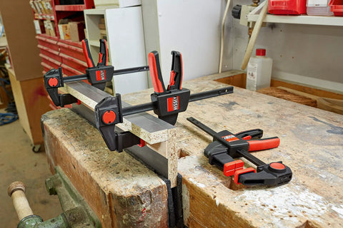 Two EZR Set Dope One Hand Table And Track Clamps with Quick Release on a wooden workbench, illustrating their use.