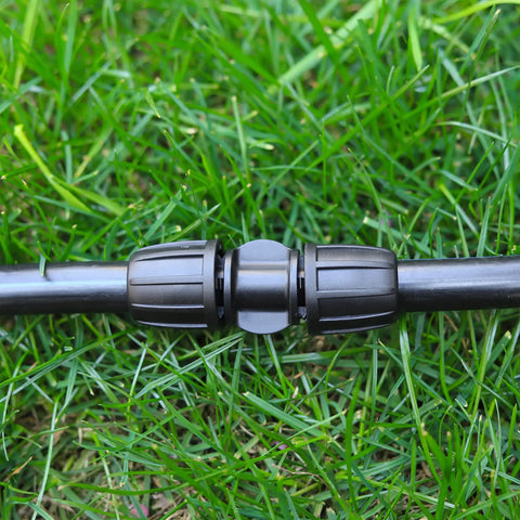 Ten Pack Half Inch Drip Irrigation Barbed Coupling Connectors installed on black tubing lying on grass