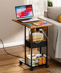 C Shaped Side Table With Charging Station And Wheels For Bedroom Living Room And Home Office Type C USB Ports And Two AC Outlets To Charge Up To Four Devices Plug And Play placed beside a sofa with a laptop and tablet on top.