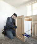 Carpenter using Heavy Duty Four Piece Clamp Set With Two Four And A Half Inch Bar Clamps And Two Two Inch Handi Clamps for cabinet installation.