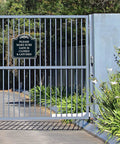 Top Shelf Outdoor Security Warning Placard Please Make Sure Gate Is Closed And Properly Latched on a gate surrounded by greenery.