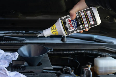 Pouring Pure Synthetic Motor Oil Stabilizer Formula into a funnel over an engine for smooth operation and pressure maintenance.