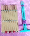 Aluminum Expanding Sewing Gauge Five In One Button Spacing Tool With Sliding Gauge Measuring Set Gold Finish For Fast Pro Button Placement Pleats Hooks And Dress Details, shown on cutting mat