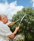 Man trimming tree with 23 Inch Hedge Shears With PowerGear2 Technology That Multiplies Power For Less Effort, SoftGrip Handles.
