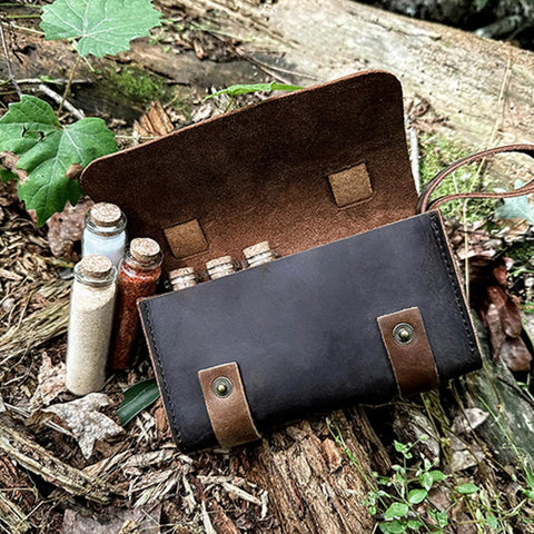 Open leather spice wallet on ground with six corked vials for travel. Leather Spice Wallet And Camping Spice Kit For Travel Seasoning Rack With Six Corked Vials For Outdoor Cooking And Flavor On The Go Durable Leather Design Built For Adventure Perfect Gift For Grilling Enthusiasts And Campers.