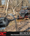Rough Country 4500 Lb ProSeries Winch For Utv And Atv With Fifty Ft Synthetic Rope 1.4HP Motor 12V Waterproof Remote Control Off Road Recovery Gear in action near muddy trail.