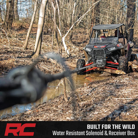 Rough Country 4500 Lb ProSeries Winch For Utv And Atv With Fifty Ft Synthetic Rope 1.4HP Motor 12V Waterproof Remote Control Off Road Recovery Gear in action near muddy trail.