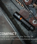 Torchy 2K Rechargeable Pocket Flashlight with 2000 Lumens on a toolbox, showing compact size in cluttered space.