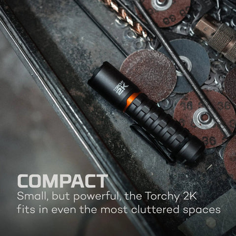 Torchy 2K Rechargeable Pocket Flashlight with 2000 Lumens on a toolbox, showing compact size in cluttered space.