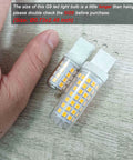 Close-up of No Flicker G9 LED Bulbs 6W Dimmable 2700K with soft warm white light next to a hand for size comparison on a wooden surface.