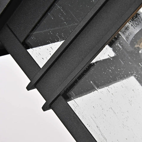 Close-up of Sleek Transitional 1 Light Textured Black Outdoor Wall Sconce With Clear Seedy Glass Downlight, angled detail of panels.