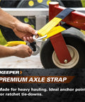 Man securing 2 Inch By 24 Inch Premium Axle Tie Down Strap with D rings onto a trailer for cargo hauling, close-up view.