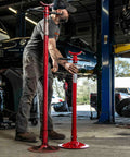 Short Underhoist Support Stand 1500 Lb Capacity Adjustable Height Range For Engine Swap And Suspension Work Fits Two Post Lifts Garage Wrenching Essential For Car Enthusiasts And Pro Mechanics, shown in a garage setting.