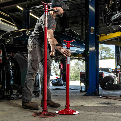 Short Underhoist Support Stand 1500 Lb Capacity Adjustable Height Range For Engine Swap And Suspension Work Fits Two Post Lifts Garage Wrenching Essential For Car Enthusiasts And Pro Mechanics, shown in a garage setting.