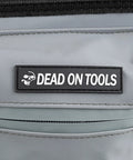 "Dead on Tools" logo on 18 Inch FlatTop Weather Resistant Tool Bag With All Terrain Bottom And Weatherproof Front Pocket 12 Interior Pockets Removable Padded Shoulder Strap Gray Assembled In The USA.