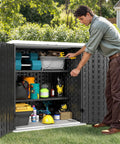 Person organizing tools in Weatherproof Outdoor Storage Cabinet With Locking Door For Patio Tools And Lawn Gear Waterproof Plastic Shed With 15 Cu Ft Capacity 2 Adjustable Shelves Dark Gray Durable Outdoor Storage Box For Garden Backyard And Deck.