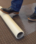 Person applying Carpet Protection Film 24 Inch By 50 Foot Self Adhesive Floor Shield Rug Guard with foot on roll