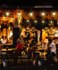 Outdoor cafe scene at night with 48 Foot LED Color Changing String Lights With Remote hanging above tables and patrons.
