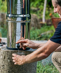 Man using Gravity-Fed Stainless Steel Countertop Water Filter System 2.25 Gallon With BB9-2 Filters outdoors