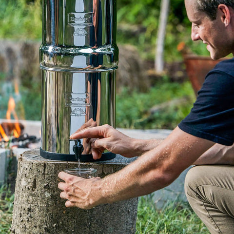 Man using Gravity-Fed Stainless Steel Countertop Water Filter System 2.25 Gallon With BB9-2 Filters outdoors