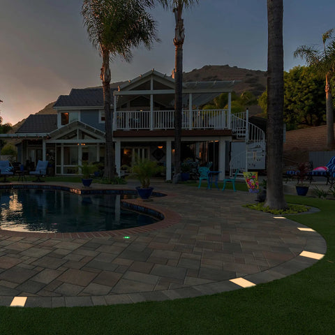 Backyard with lit 6x9 Inch Paver Light Warm White 2700K Drive Over Rated 12V Waterproof Landscape Lighting by poolside.