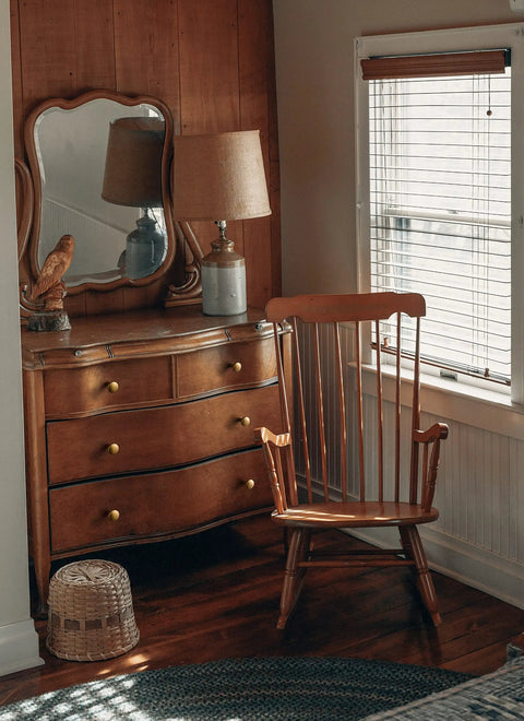 Vintage wooden dresser with antique brass knobs next to a wooden chair, enhancing retro charm in a cozy interior setting.