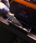 Eight Inch Bench Grinder Powered By A Beefy Four Point Eight Amp Motor Hitting 3450 RPM, Features Adjustable Eye Guards With Bright LED Work Lights And Cooling Tray, Straight Up Shop Essential For Knife Sharpening And Metal Jobs, showing a person sharpening a knife over the cooling tray.