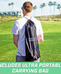 Person carrying Ladder Toss Game Set with Carrying Case, view of portable bag on back, green lawn and palm trees in background.