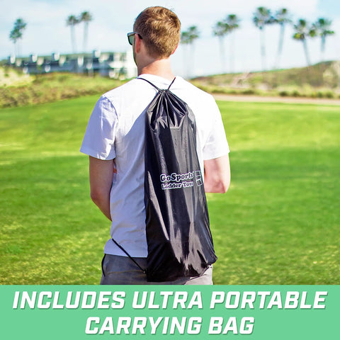 Person carrying Ladder Toss Game Set with Carrying Case, view of portable bag on back, green lawn and palm trees in background.