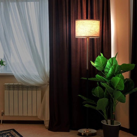 Emery LED Floor Lamp With Drum Shade, Tall Mid Century Standing Light, in modern living room with brass finish next to plant