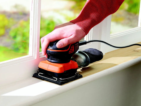 User operating Quarter Sheet Orbital Palm Sander Professional Grade 220 Watt Motor on wooden window sill.