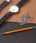 Heavy Duty Watch Band Pins And Spring Bar Tool Kit With 76 Stainless Steel Pins shown with watch and tool on leather surface.