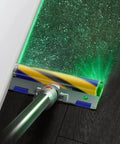 V15 Detect Cordless Vacuum Cleaner with Laser Illumination revealing dust on dark floor, shown in Yellow Nickel Finish.