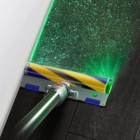 V15 Detect Cordless Vacuum Cleaner with Laser Illumination revealing dust on dark floor, shown in Yellow Nickel Finish.