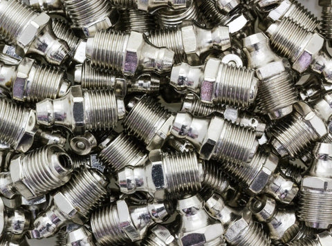 Pile of metal fittings from All In One Grease Fitting Tool For 1/8 And 7/16 NPT used in cars, trucks, tractors, and heavy equipment.