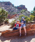 Two children on a red rock trail with Reservoir Big Bite Valve Set In Multi Color For Hydration Systems, One Size Fits All Reservoirs, Self Seals After Each Sip To Stop Drips, Patented One Piece Silicone Design, Lifetime Guarantee