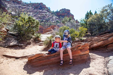 Two children on a red rock trail with Reservoir Big Bite Valve Set In Multi Color For Hydration Systems, One Size Fits All Reservoirs, Self Seals After Each Sip To Stop Drips, Patented One Piece Silicone Design, Lifetime Guarantee