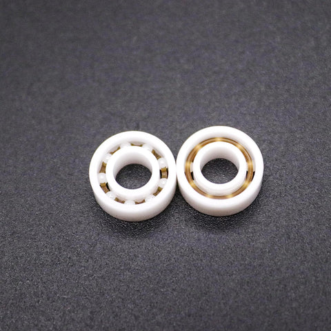 Two MR115 5x11x4 mm full ceramic bearings; front view shows ceramic balls, side view shows gold inner race.