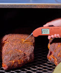 Hand using Top Rated No. 1 Instant-Read Thermometer For Precision Cooking, One-Second Read, Cayenne Pepper Red, on grilled meat