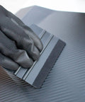 Black gloved hand using squeegee on car vinyl from 9 In 1 Vinyl Wrap Tools Kit With Heat Gun For Car Wrapping And Window Tinting Includes Squeegees, Wrapping Knives, Vinyl Cutter, Magnet Holder, Working Gloves.