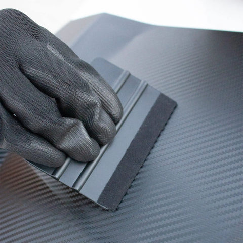 Black gloved hand using squeegee on car vinyl from 9 In 1 Vinyl Wrap Tools Kit With Heat Gun For Car Wrapping And Window Tinting Includes Squeegees, Wrapping Knives, Vinyl Cutter, Magnet Holder, Working Gloves.