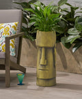 Outdoor Easter Island Tiki Urn Planter in Antique Green Finish on patio with plants, cast stone vase beside chair.