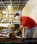 Person working under CFL light bulb with lifespan of over nine years in an active space.