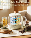 Glass electric kettle with removable infuser, surrounded by jars of tea leaves and coffee beans, on a wooden countertop.