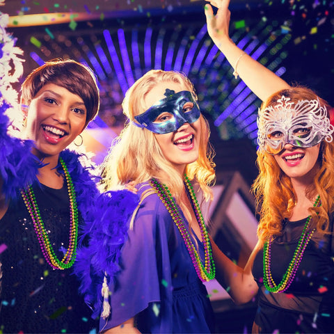 Three women at a party wearing Mardi Gras Beads Necklaces 24 Pack, 33 Inch Round Beads In Green Purple Gold, carnival masks.